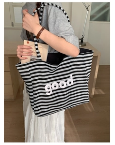 Detail of striped canvas tote bag with good print showing wide shoulder strap and capacity