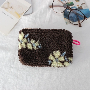 Detailed macro shot of vintage plush makeup bag with floral patterns and a pink zipper pull