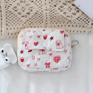 Close-up of quilted floral coin purse with red strawberry and dog prints on white fabric