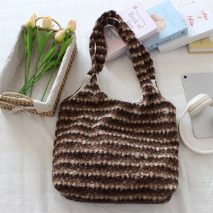 Flat lay of a striped plush tote bag with daily essentials like tablets and flowers
