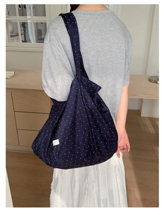 Detail of navy blue polka dot canvas tote bag featuring soft texture and woven label