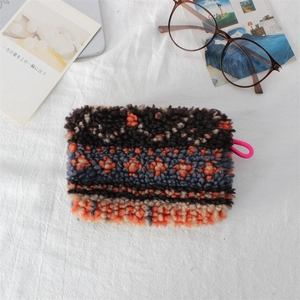 Detail of plush cosmetic bag with colorful geometric patterns and pink handle