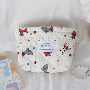 Flat lay of white quilted cosmetic bag featuring cute cartoon animals and metal zipper detail