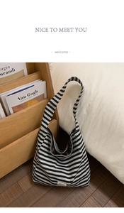 Detail view of large striped hobo shoulder bag with a wide strap on a wooden magazine rack