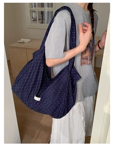 Detail of the navy blue polka dot canvas tote bag shown worn on the shoulder by a model