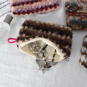 Close-up of curly plush makeup bag showing soft texture and metal zipper with jewelry inside