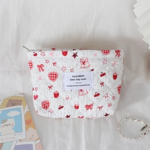 Close-up of white quilted cosmetic bag with cute red strawberry and bunny patterns