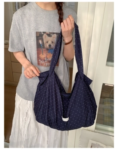 Detail of navy blue polka dot canvas tote bag featuring a white woven label on the bottom