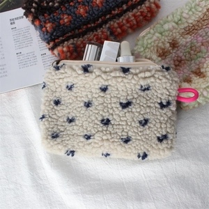 Close-up of plush heart-patterned pouch with cosmetics on a soft fabric background