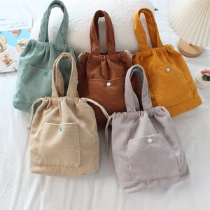 Detailed collection of colorful corduroy drawstring handbags in warm interior setting