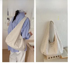 Close-up of polka dot canvas tote bag with wide strap and minimalist woven label details