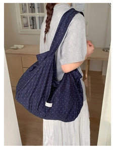 Detail of navy blue polka dot canvas tote bag showing soft fabric texture and woven label