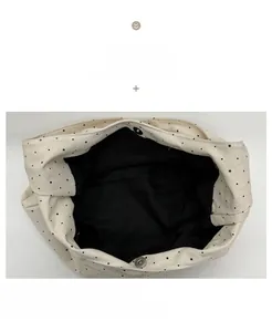 Detail view of beige canvas star print tote with black lining and magnetic buckle