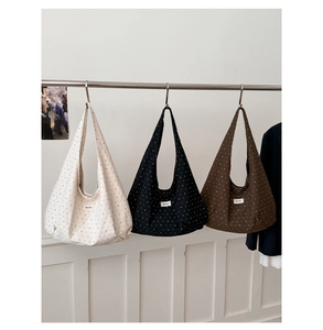Detailed view of three polka dot canvas tote bags hanging in beige, black, and brown