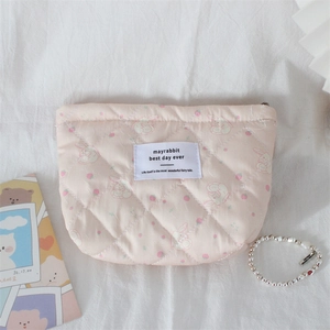 Close-up of quilted pink fabric showing cute rabbit and strawberry patterns on makeup bag