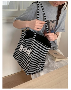 Detail of striped canvas tote bag with good print shown in a French lifestyle setting