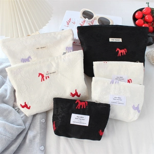 Detailed close-up of jacquard satin pouch with embroidered pony motifs and brand label
