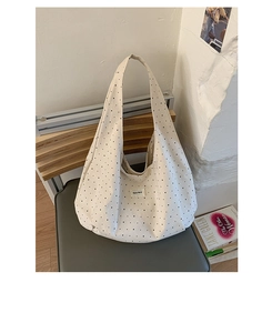 Close-up of polka dot canvas tote bag with woven label on a minimalist grey chair