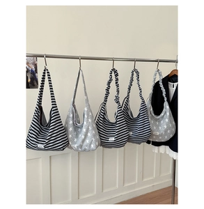 Detail of canvas hobo bags featuring classic stripes and star patterns on a metal rack