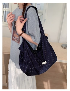 Detail of navy blue polka dot canvas tote bag with brand label and spacious interior