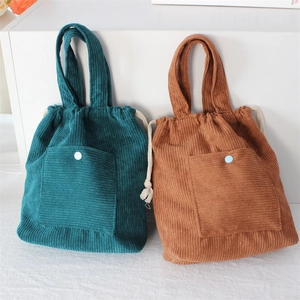 Detail of corduroy drawstring handbags in dark green and caramel with textured fabric