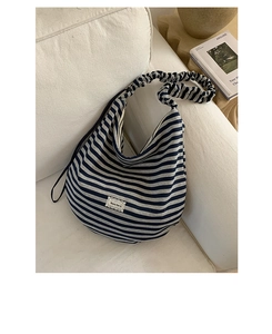 Close-up of striped hobo bag with ruffled strap on a white sofa in a cozy interior