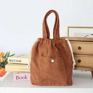 Detailed close-up of brown corduroy tote bag with drawstring closure and blue button
