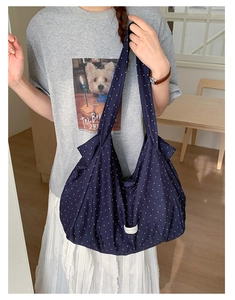 Detailed view of dark blue polka dot canvas tote with white woven label and soft texture