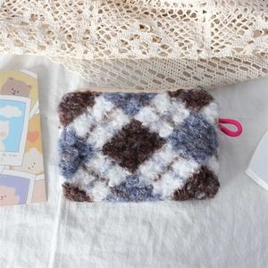 Detail of plush checkered makeup bag with lamb wool texture and sturdy zipper closure