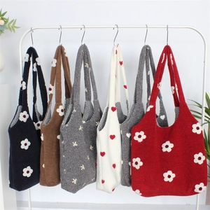 Detail of multi-colored knit tote bags with daisy embroidery and checkered lining