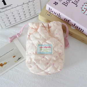 Detail of pink quilted drawstring bag with strawberry and rabbit print texture