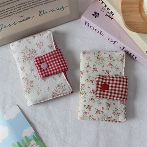 Close-up of floral fabric notebook cover featuring cotton texture and red checkered clasp