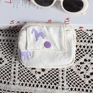 Detailed close-up of white jacquard coin purse with purple horse embroidery on lace cloth