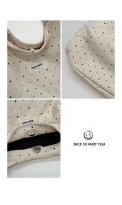 Detail of canvas tote featuring black star print, magnetic clasp and lace brand label
