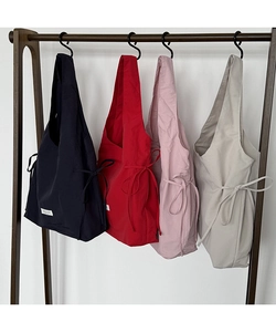 Detail view of nylon tote bags with side drawstrings and minimalist labels in four colors