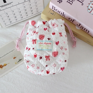 Detail of white quilted drawstring bag with red strawberry pattern and protective texture