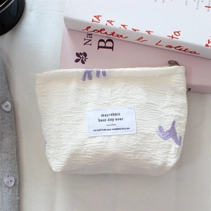 Detail of satin jacquard makeup bag with purple animal embroidery and zip closure