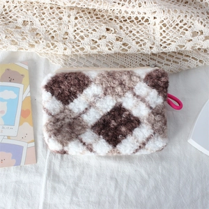 Detail of plush checkered makeup bag with soft fleece texture and sturdy metal zipper