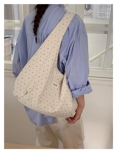 Detailed close-up of white canvas tote bag with black star pattern and logo patch