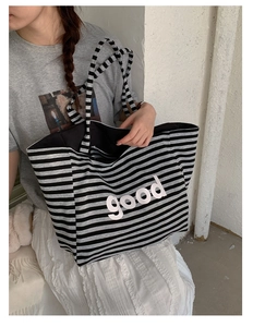 Close-up of a striped tote bag with pink good lettering on soft knit fabric