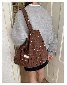 Rear view of woman carrying a brown polka dot canvas tote bag for daily casual commute