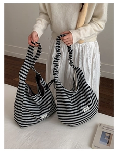Detail of striped knit tote bag showing the unique ruffled shoulder strap and logo label