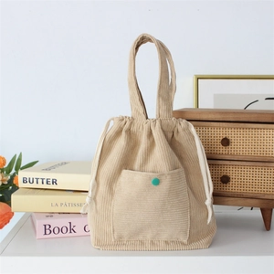 Detail of beige corduroy drawstring handbag with green button pocket and white cotton ropes