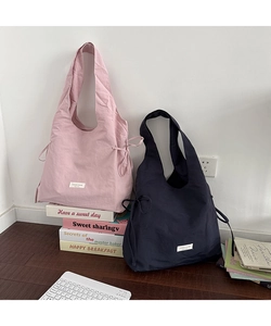 Detail view of pink and navy nylon tote bags with side drawstrings in home setting