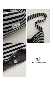 Detail of the magnetic snap closure and internal dark lining of the striped tote bag