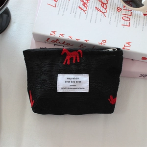 Detail of black jacquard satin makeup bag with red horse embroidery and zipper