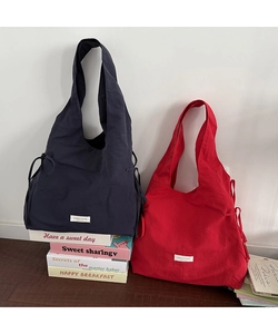 Detail of red and navy nylon tote bags with side drawstring accents on colorful books