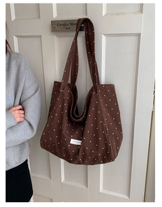 Detail of canvas tote bag with white polka dots on brown fabric and branded woven label