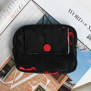 Macro detail of black jacquard coin purse with red embroidery and metal ring zipper