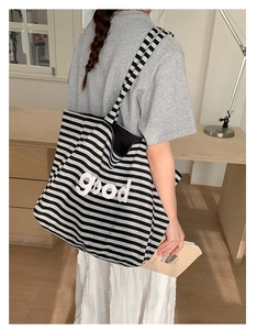 Close-up of a large capacity striped canvas tote bag with bold white good lettering
